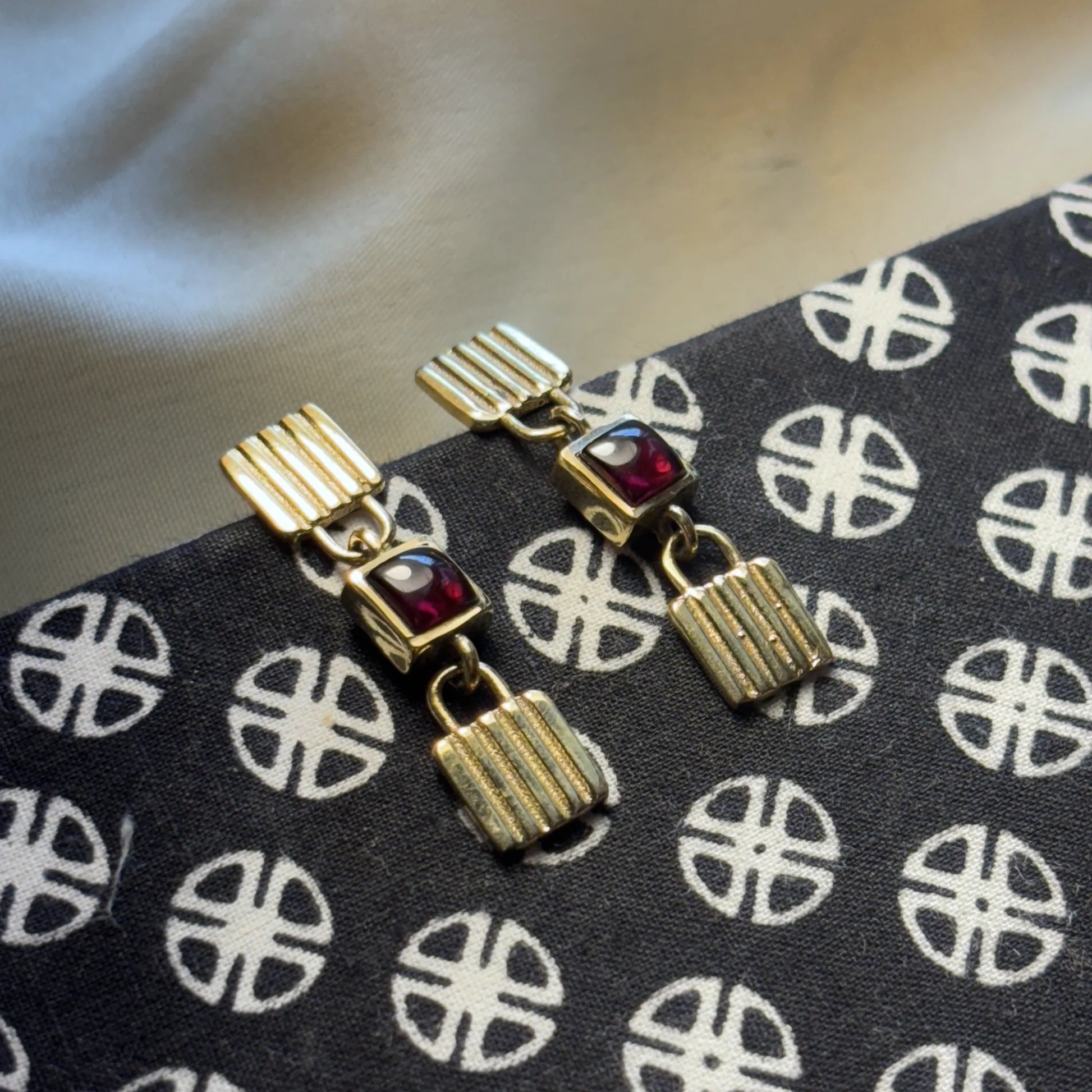 Brass garnet drop earrings placed on black and beige texture