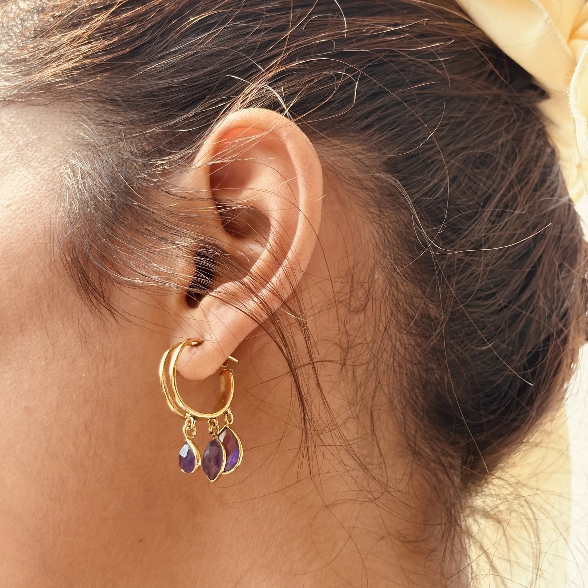 Amethyst charm hoops worn on ear with yellow scarf