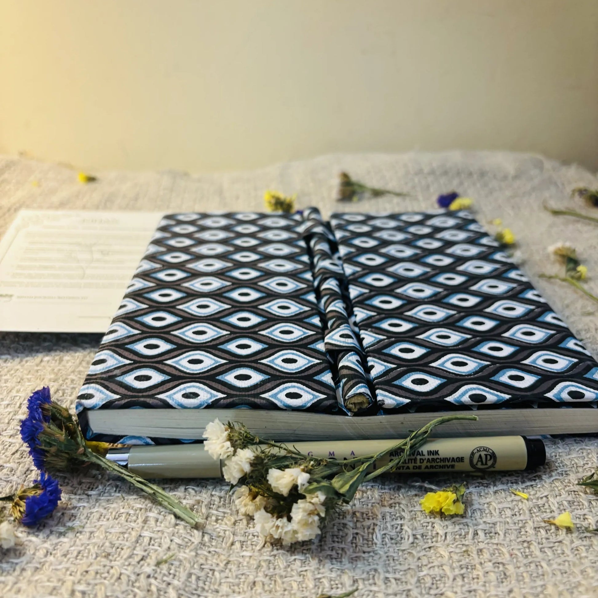 Handmade paper pen journal in evil eye - flatlay view