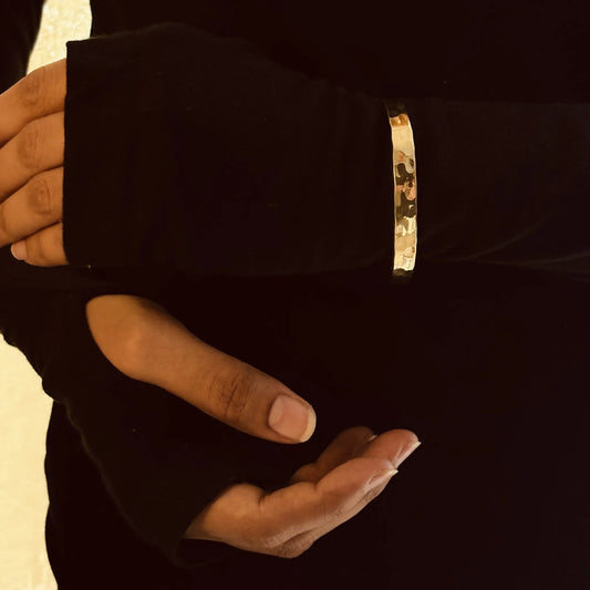 Close-up of a brass hammered cuff worn on arm, hand lifted