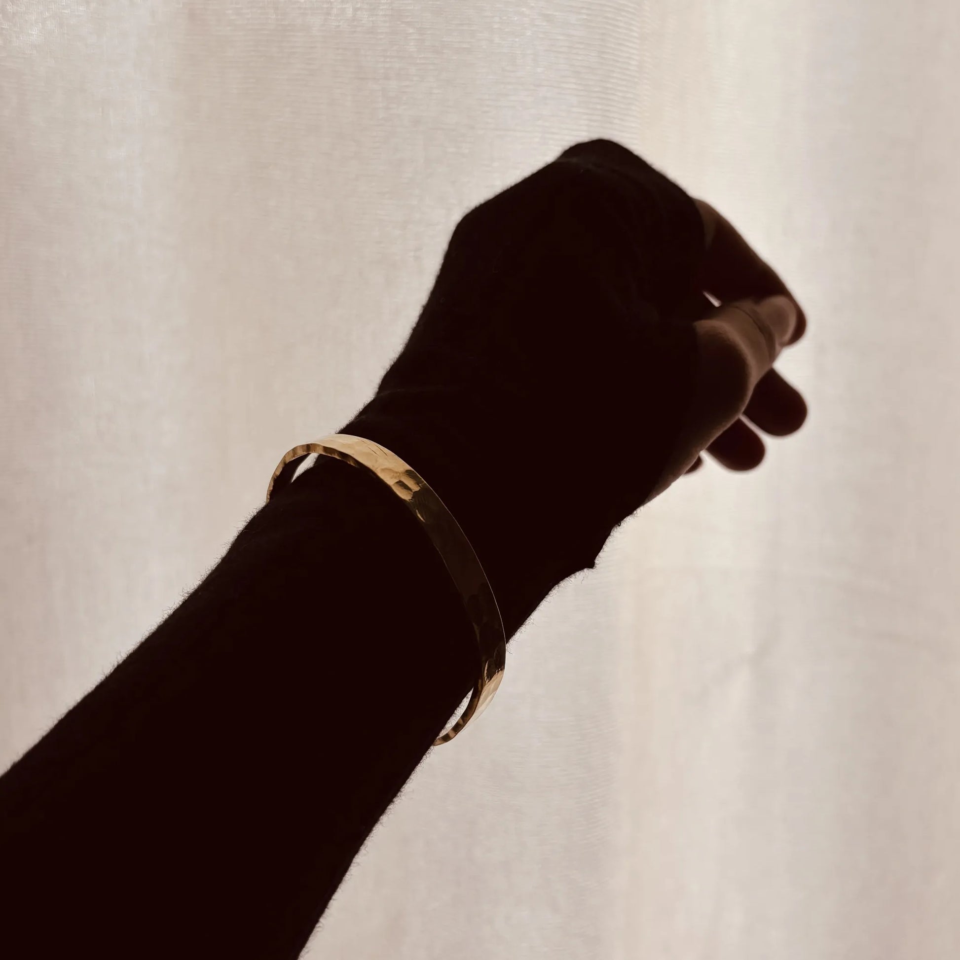 Brass cuff in silhouette against window light
